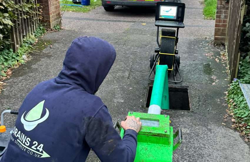 A drainage engineer in Bournemouth performing a no-dig pipe relining on a residential driveway using CIPP equipment, representing efficient drain repair without excavation.