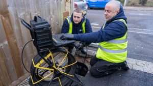 A drainage engineer in Bournemouth operating a CCTV inspection camera van outside a residential home, representing detailed pre-purchase drain surveys for homebuyers.
