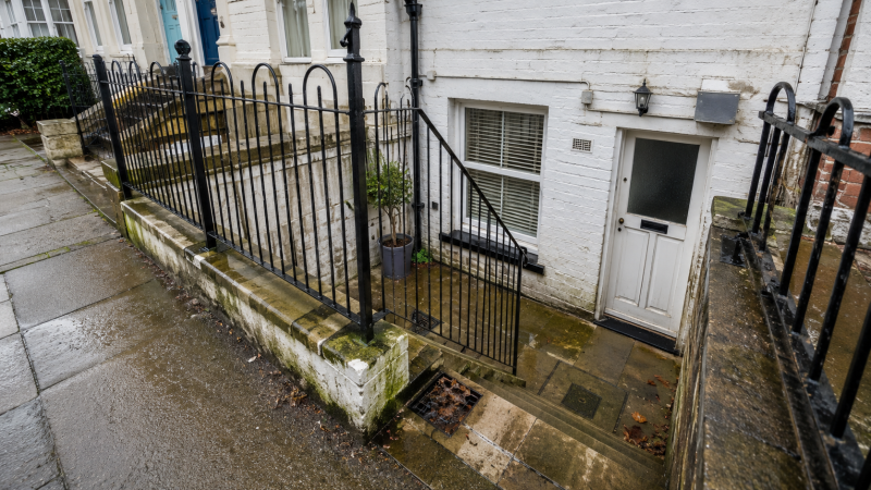 Bournemouth basement flat entrance with damp paving, lower-level doorway and drainage access showing possible basement flat drain problems.