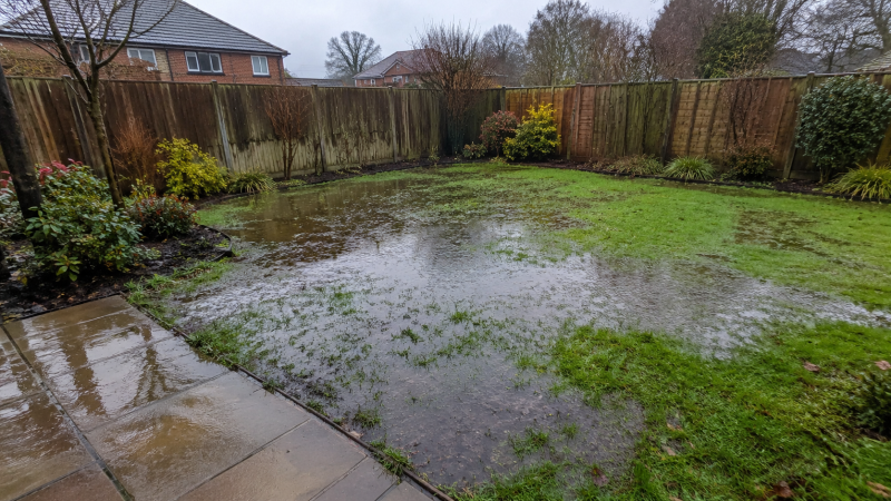 Bournemouth driveway after heavy rain with standing water, blocked surface water gully, damp paving and drainage equipment nearby.